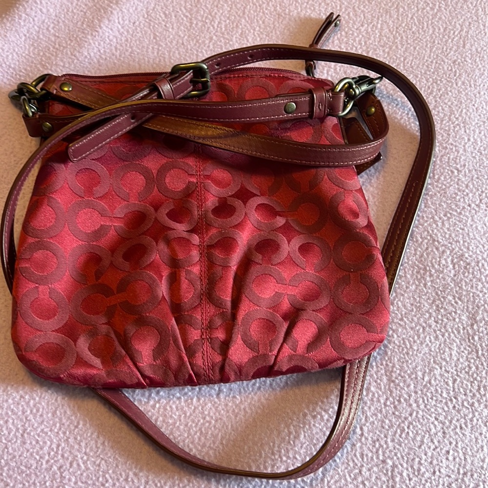 Small Coach crossbody in maroon.